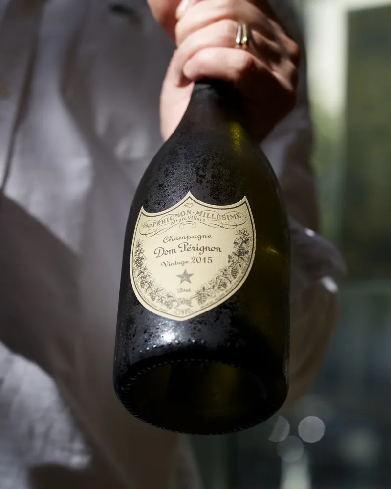 Une bouteille de champagne millésimé présentée par le service