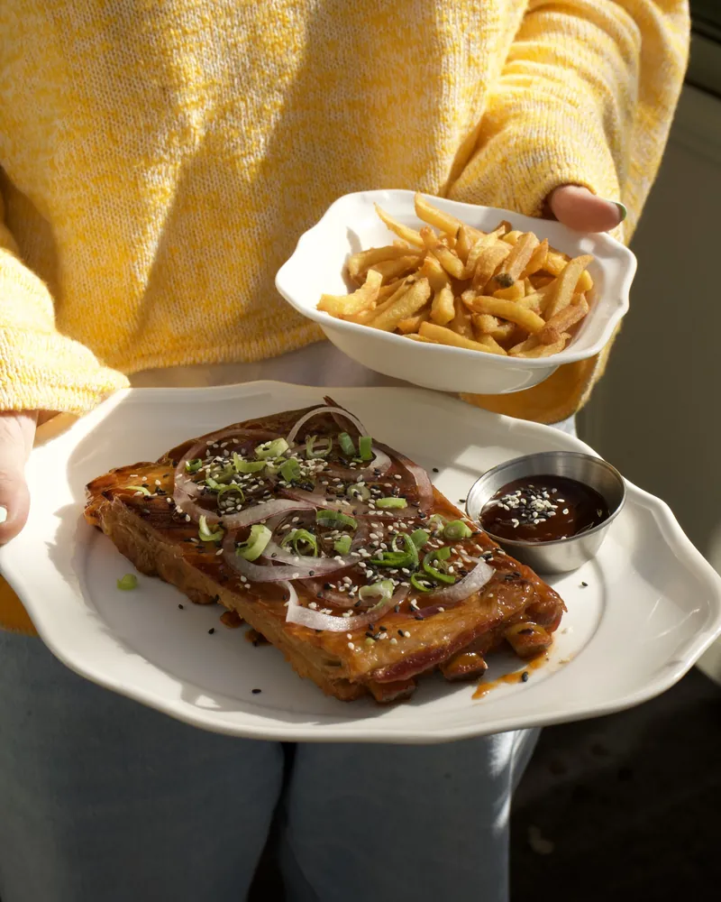 Un travers de porc laqué servi avec un bol de frites maison et sa sauce